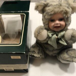 Geppeddo porcelain doll with a cat outfit that is striped and sage bow with bell